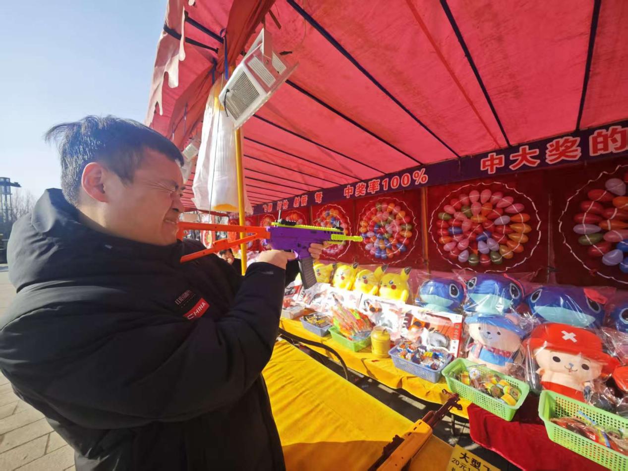 小镇的游戏摊位前,顾客在进行射击游戏。人民网记者 王天乐摄